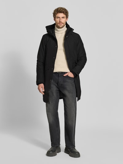 Männermodel trägt schwarzen Regular Fit Parka mit Kapuze Modell 'Kenny' von Didriksons, gerade Passform, Eingrifftaschen, Ganzkörperansicht von vorne. Rückenlänge 99 cm, Schulterbreite 48 cm, Brustweite 59 cm, Ärmellänge 72 cm.