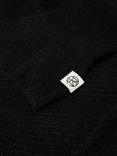 Produktfoto, schwarze Mütze mit Schal Modell 'BONDIE' von MSCH Copenhagen, Material-Mix mit Alpaka-Anteil, Label-Detail sichtbar.