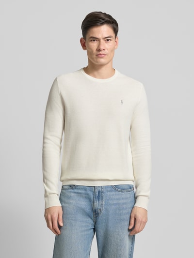 Męski model nosi Sweter z dzianiny z wyhaftowanym logo od Polo Ralph Lauren z bawełny, krój regular fit, prążkowane wykończenia, okrągły dekolt, długość tyłu 72 cm, długość rękawów 69 cm, kolor jasny, gładka faktura, widok z przodu, całopostaciowy.