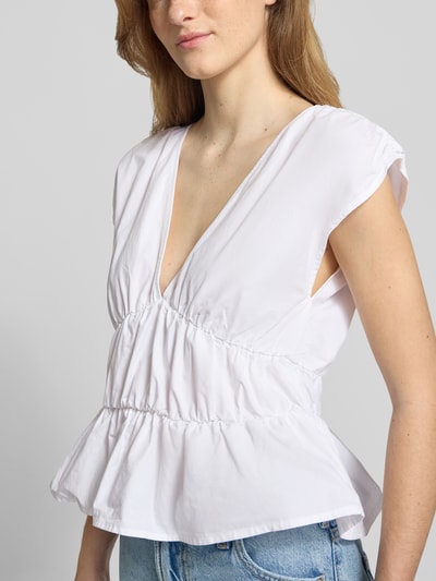 Frauenmodel trägt Peplum Top mit V-Ausschnitt von Gina Tricot aus Reine Baumwolle, Körpernaher-Schnitt, Raffungen, Nahaufnahme Oberkörper.