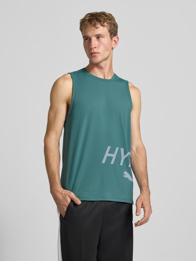 Mężczyzna nosi Regular Fit Sport-T-Shirt mit Rundhalsausschnitt von PUMA w kolorze zielonym z białym nadrukiem, Ganzkörperansicht von vorne, Herren Sport-T-Shirt von PUMA Performance