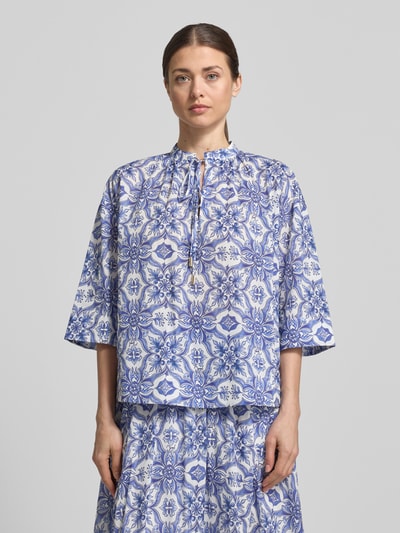 Kobiece modelka nosi bluzkę Regular Fit Bluse mit Schlüsselloch-Ausschnitt Modell 'Beyda' od JOOP!, mieszanka modalu, wzór na całej powierzchni, wycięcie w kształcie łezki, wiązanie, rękaw o dł. 3/4, długość tyłu w rozmiarze 36: 58 cm, długość rękawów w rozmiarze 36: 32 cm, widok na całą sylwetkę z przodu.