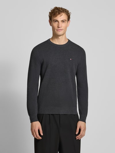 Męski model nosi Regular Fit Pullover aus reiner Baumwolle von Tommy Hilfiger w kolorze ciemnoszarym, gładka faktura, całkowity widok z przodu.