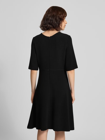 Frauenmodel trägt Minikleid aus Viskose-Mix mit Rundhalsausschnitt von Emporio Armani, taillierte Passform, schwarze Farbe, Halbarm, Ganzkörperansicht Rückansicht.