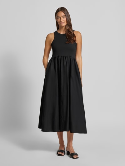 Frauenmodel trägt Midikleid mit Rundhalsausschnitt Modell 'MIRI' von YAS aus Baumwoll-Elasthan-Mix in Schwarz, A-Linie, Ganzkörperansicht von vorne. Rückenlänge bei Größe S: 125 cm, Brustweite: 37 cm.