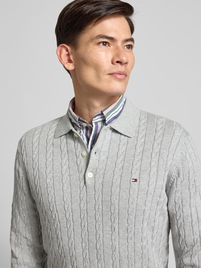 Männermodel trägt Regular Fit Strickpullover aus reiner Baumwolle von Tommy Hilfiger, Optik: Unifarben, Zopfmuster, Logo-Applikation, Polokragen, Langarm, Materialverarbeitung: Strick, Nahaufnahme Oberkörper.