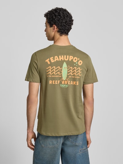 Männermodel trägt T-Shirt mit Motiv-Print Modell 'SUN ISLAND' von Blend in Olivgrün, reine Baumwolle, Regular Fit, Rückenlänge 71 cm, Ganzkörperansicht Rückansicht.