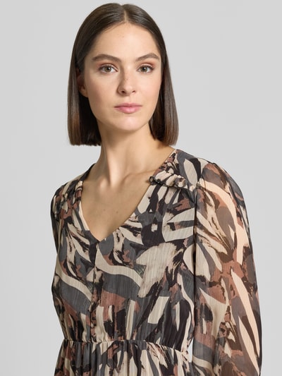 Frauenmodel trägt Minikleid mit V-Ausschnitt Modell 'Ev44aa' von ZABAIONE in Braun-Beige mit abstraktem Muster, Nahaufnahme Oberkörper. Chiffon, taillierter Schnitt, elastische Ärmelabschlüsse, blickdichtes Unterkleid, Größe S: Rückenlänge 93 cm, Brustweite 45 cm, Ärmellänge 58 cm.