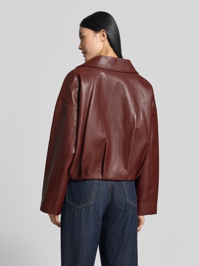 Frauenmodel trägt Regular Fit Jacke in Leder-Optik Modell 'Dante' von MANGO in Dunkelrot mit Falten-Optik, Ganzkörperansicht Rückansicht.