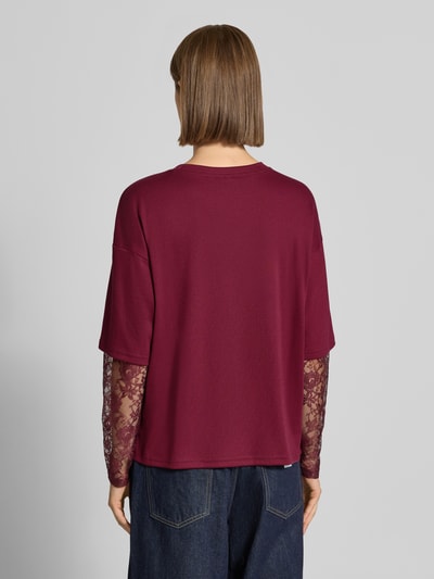 Frauenmodel trägt Regular Fit Langarmshirt mit Viskose-Anteil Modell 'TAHLIA' von ONLY in Dunkelrot mit Spitzenärmeln, Damen Langarmshirt von ONLY, Ganzkörperansicht Rückansicht.