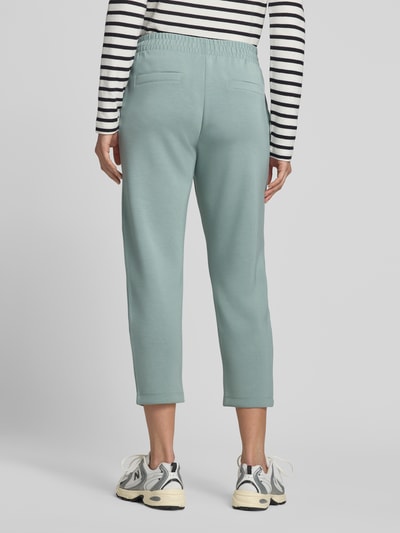 Vrouwenmodel draagt Cropped Sweatpants mit elastischem Bund und Eingrifftaschen van Christian Berg Woman, materiaalmix met modal, kort, steekzakken, Ganzkörperansicht Rückansicht.