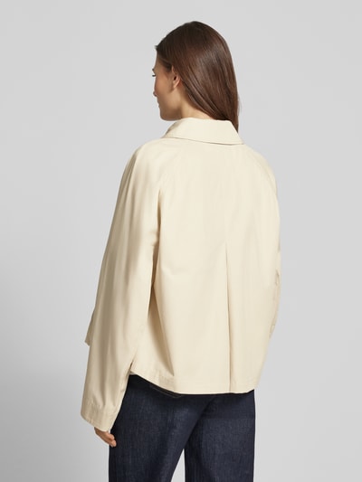 Modelka kobieca ma na sobie Relaxed Fit Trenchcoat aus reiner Baumwolle od Tommy Hilfiger, efekt: jednolity kolor, krój relaxed fit, wykładany kołnierz, listwa guzikowa, krój krótki, detal z logo, proste zakończenie rękawów, hydrofobowy, splot twill, bawełna, zdjęcie całej sylwetki z tyłu.