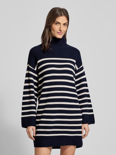 Frauenmodel trägt Mini-Strickkleid aus Woll-Kaschmir-Mix Modell 'AREENA' von Lauren Ralph Lauren, Dunkelblau mit weißen Streifen, Oversized, Rollkragen, gerippte Abschlüsse, Minilänge, Rückenlänge 83 cm, Ärmellänge 67 cm, Ganzkörperansicht von vorne.
