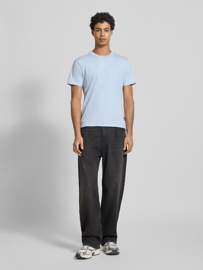 Männermodel trägt Regular Fit T-Shirt mit Logo-Print von Replay, Herren T-Shirt aus reiner Baumwolle, Rundhalsausschnitt, Ganzkörperansicht von vorne.