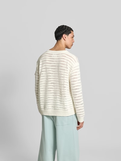 Männermodel trägt Relaxed Fit Pullover in Strick-Optik von MM6 Maison Margiela aus reiner Baumwolle in Creme mit Rundhalsausschnitt, elastische Abschlüsse, Rückenlänge bei Größe M: 67 cm, Ganzkörperansicht Rückansicht.