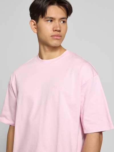 Männermodel draagt Oversized T-shirt met logo en ronde hals van REVIEW, puur katoen, oversized, logoprint, ruglengte maat M 68 cm, Nahaufnahme Oberkörper.