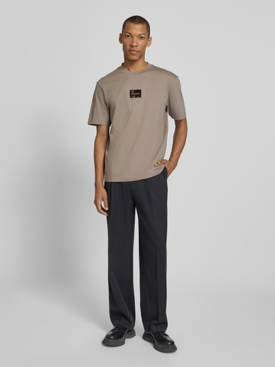 Männermodel trägt Regular Fit T-Shirt aus reiner Baumwolle Modell 'DUMEON' von HUGO in Unifarben mit Label-Applikation, Ganzkörperansicht von vorne