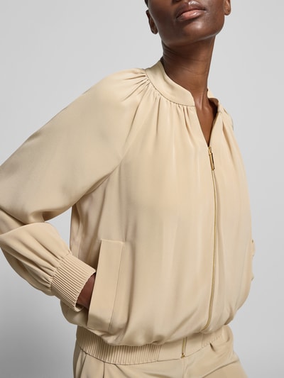 Frauenmodel trägt Blouson mit Reißverschluss von Joseph in Beige, Material-Mix, Stehkragen, Eingrifftaschen, lockere Passform, Nahaufnahme Oberkörper.