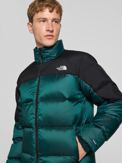 Männermodel trägt Regular Fit Jacke mit Daunen-Feder-Füllung Modell 'Diabolo' von The North Face, Stepp-Optik in Grün und Schwarz, Nahaufnahme Oberkörper. Kontext: Herren Jacke mit Stehkragen, Logo-Stitching, Größenangaben M: Rückenlänge 70 cm, Schulterbreite 47 cm, Brustweite 58 cm, Ärmellänge 69 cm.