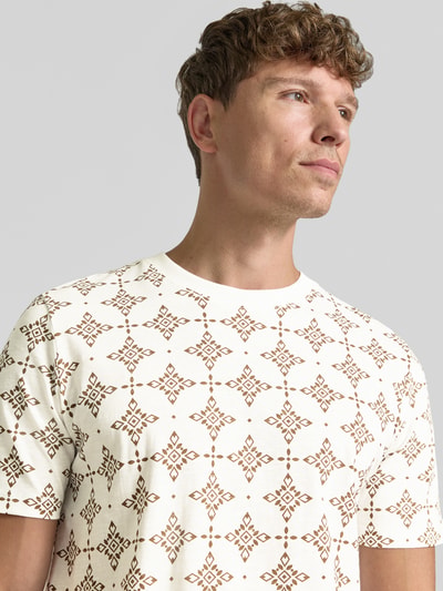 Männermodel trägt Regular Fit T-Shirt aus reiner Baumwolle von s.Oliver RED LABEL, creme met bruin grafisch patroon, Nahaufnahme Oberkörper