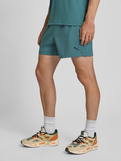Männermodel trägt Regular Fit Sportshorts mit Logo-Print Modell 'TAD ESSENTIALS' von PUMA in Türkis, Herren Sportshorts, Ganzkörperansicht von vorne