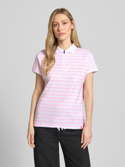 Kobiece modelka nosi Regular Fit Poloshirt mit Reißverschluss von FIRE + ICE, wzór na całej powierzchni, tunel, długość tyłu w rozmiarze S 62 cm, widok całej sylwetki z przodu.