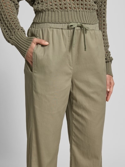 Frauenmodel trägt Stoffhose mit Lyocell-Anteil von Juvia in Beige mit Eingrifftaschen und elastischem Bund, Nahaufnahme Oberkörper. Baumwoll-Mix, Straight Fit.