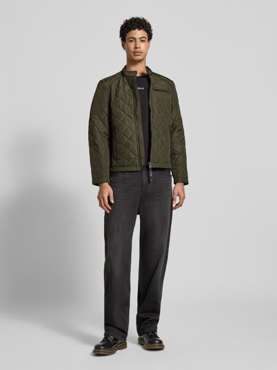 Männermodel trägt Regular Fit Jacke in Stepp-Optik von Replay in Olivgrün mit Stehkragen, Reißverschluss, Brusttasche, Ganzkörperansicht von vorne.