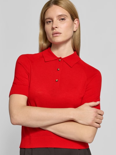 Frauenmodel trägt Poloshirt aus reiner Wolle von Victoria Beckham in Rot, Strick-Optik, Halbarm, Regular Fit, Nahaufnahme Oberkörper.