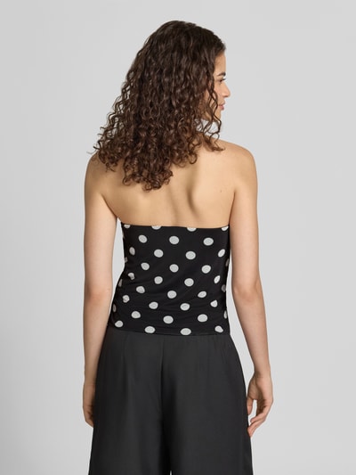 Frauenmodel trägt Neckholder-Top im Allover-Look Modell 'DOTTIE' von NOISY MAY®, schwarz mit weißen Punkten, Ganzkörperansicht Rückansicht. Material-Mix mit Stretch-Anteil, Slim Fit, Rückenlänge bei Größe S 30 cm.
