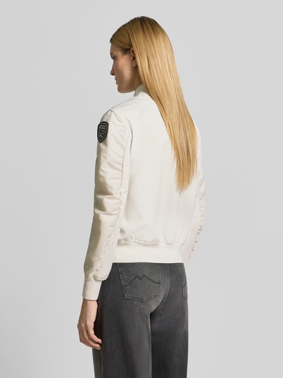 Frauenmodel trägt Bomberjacke mit Reißverschlusstaschen Modell 'LAURIE' von Blauer Usa in Creme, Label-Patch, Rückenansicht, Ganzkörperansicht Rückansicht.
