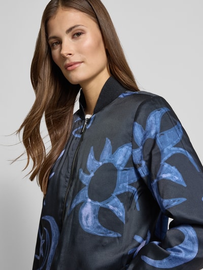 Vrouwenmodel draagt Jacke met Stehkragen en Eingrifftaschen van Scotch & Soda in regular fit, blauw-zwart dessin, labeldetail, Nahaufnahme bovenlichaam. Ruglengte maat S: 57 cm, schouderbreedte: 44 cm, borstwijdte: 50 cm, mouwlengte: 63 cm.