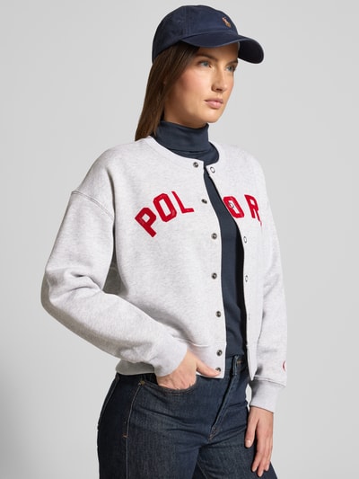 Frauenmodel trägt Sweatjacke mit Label-Print und Knopfleiste von Polo Ralph Lauren aus Baumwoll-Mix, Relaxed-Fit, Rundhalsausschnitt, Ganzkörperansicht von vorne.