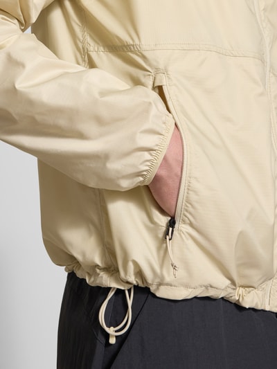 Männermodel trägt Windbreaker mit Logo und ritszakken van The North Face in regular fit, licht beige, detailopname zijaanzicht taille.
