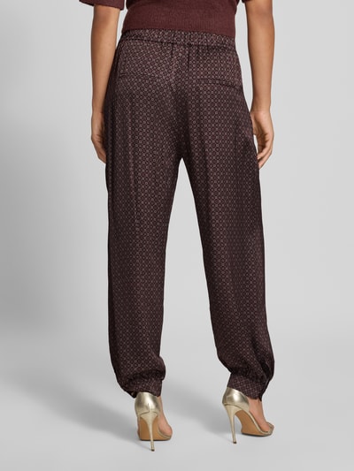Frauenmodel trägt Loose Fit Weite Hose mit Allover-Muster von Jake*s aus der Jake*s Collection in dunklem Rot mit kleinen Mustern, Ganzkörperansicht Rückansicht.