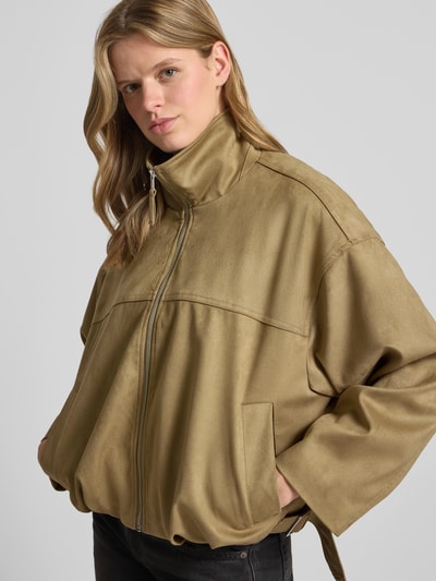 Frauenmodel trägt Jacke in Leder-Optik mit Reißverschluss und Eingrifftaschen von Gina Tricot, Relaxed-Fit, Material-Mix, Nahaufnahme Oberkörper.