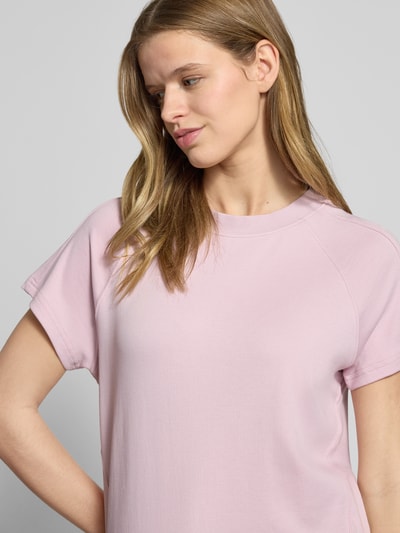 Kobiece model prezentuje Damski t-shirt z bawełny o kroju regular fit, model 'Raglan' z naszywką z logo marki G-Star Raw, okrągły dekolt, elastyczne wykończenie; długość tyłu w rozmiarze S: 57 cm, kolor jasnoróżowy, tekstura gładka, półzbliżenie górnej części ciała.