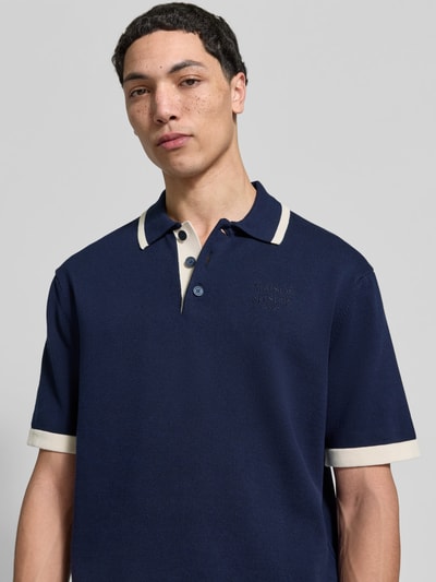 Männermodel trägt Regular Fit Poloshirt aus Baumwolle von MAISON KITSUNÉ in Dunkelblau mit Polokragen und Strick-Optik, Nahaufnahme Oberkörper.