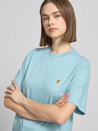 Frauenmodel trägt T-Shirt mit Label-Stitching von Carhartt Work In Progress, Damen T-Shirt aus reiner Bio-Baumwolle, Relaxed-Fit, Rundhalsausschnitt, hellblau, Nahaufnahme Oberkörper.