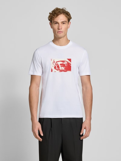 Männermodel trägt weißes Regular Fit T-Shirt aus reiner Baumwolle Modell 'Dirom' von HUGO, roter Print vorne, Ganzkörperansicht von vorne, Herren T-Shirt von HUGO.