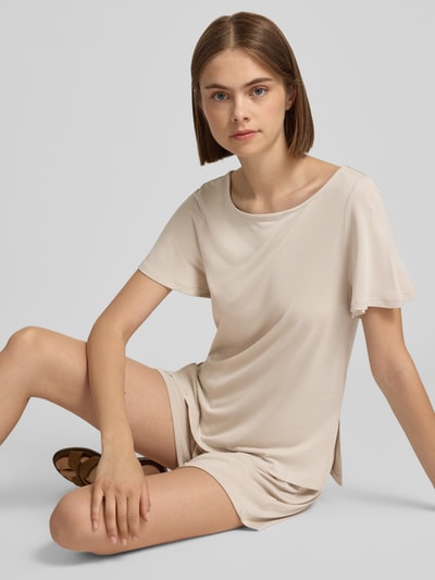 Kobiece model prezentuje Damski t-shirt krój regular fit model 'PCANORA' od PIECES w kolorze beżowym, lekka tkanina, zdjęcie całej sylwetki z przodu.