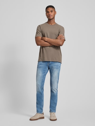 Männermodel trägt Slim Fit Jeans aus Baumwoll-Mix Modell 'DELAWARE' von BOSS Orange, Used Denim mit Label Patch, Ganzkörperansicht von vorne.