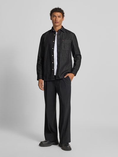 Männermodel trägt Regular Fit Jeanshemd aus reiner Baumwolle von Tommy Hilfiger in Black Denim mit Kentkragen, Ganzkörperansicht von vorne.