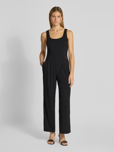Modelka kobieca nosi kombinezon z okrągłym dekoltem od Calvin Klein Womenswear, czarny, krój regular fit, detal z logo, całkowita długość 140 cm, szerokość w rozmiarze S: 33 cm, długość wewnętrzna nogawki 74 cm, plisy z przodu, zdjęcie: całkowity widok z przodu.