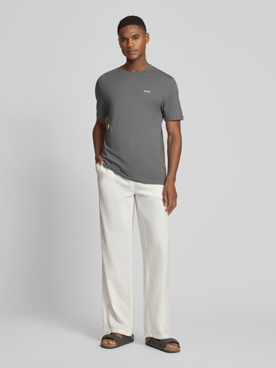 Männermodel trägt Regular Fit T-Shirt aus reiner Baumwolle Modell 'DERO222' von HUGO in Optik: Unifarben mit Label-Print, Ganzkörperansicht von vorne.