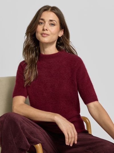 Frauenmodel trägt Wollshirt mit Stehkragen von Christian Berg Woman in dunklem Rot, taillierte Passform, gerippte Abschlüsse, 1/2-Arm Design, Oberkörper-Nahaufnahme.