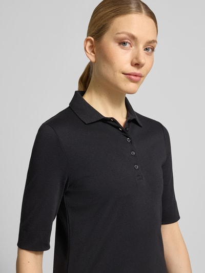 Kobiece model prezentuje Slim Fit Poloshirt mit Knopfleiste und 1/2-Arm od Christian Berg Woman, czarna bawełna, krój slim fit, listwa guzikowa, rękaw o dł. 1/2, długość tyłu w rozmiarze 36: 61 cm, zbliżenie na górną część ciała z przodu