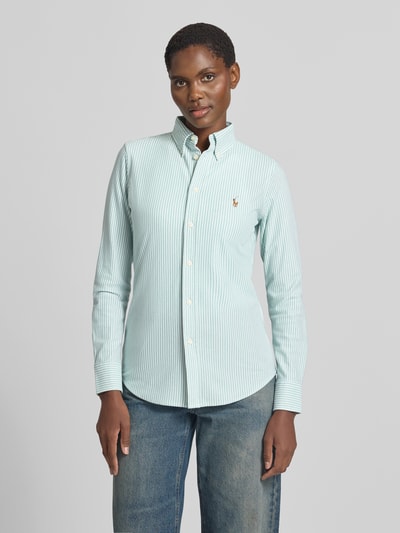 Frauenmodel trägt Regular Fit Hemdbluse aus reiner Baumwolle von Polo Ralph Lauren, hellgrün-weiß gestreift, glatte Textur, Ganzkörperansicht von vorne.