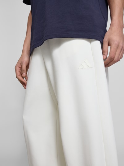 Männermodel trägt Regular Fit Sweatpants mit Modal-Baumwoll-Anteil von adidas Sportswear, unifarben, Nahaufnahme Oberkörper.
