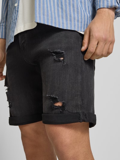 Männermodel trägt Jeansshorts mit Umschlag Modell 'RICK' von Jack & Jones, dunkel, Used-Look, sichtbare Struktur, Nahaufnahme Oberschenkel, Regular Fit, Stretch-Anteil.
